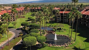 A resort with multiple buildings, a golf course, and a central water feature surrounded by palm trees and well-maintained lawns. - Vacation Retreat at Kamaole Sands, Steps from Kamaole Beach III! (Kihei)