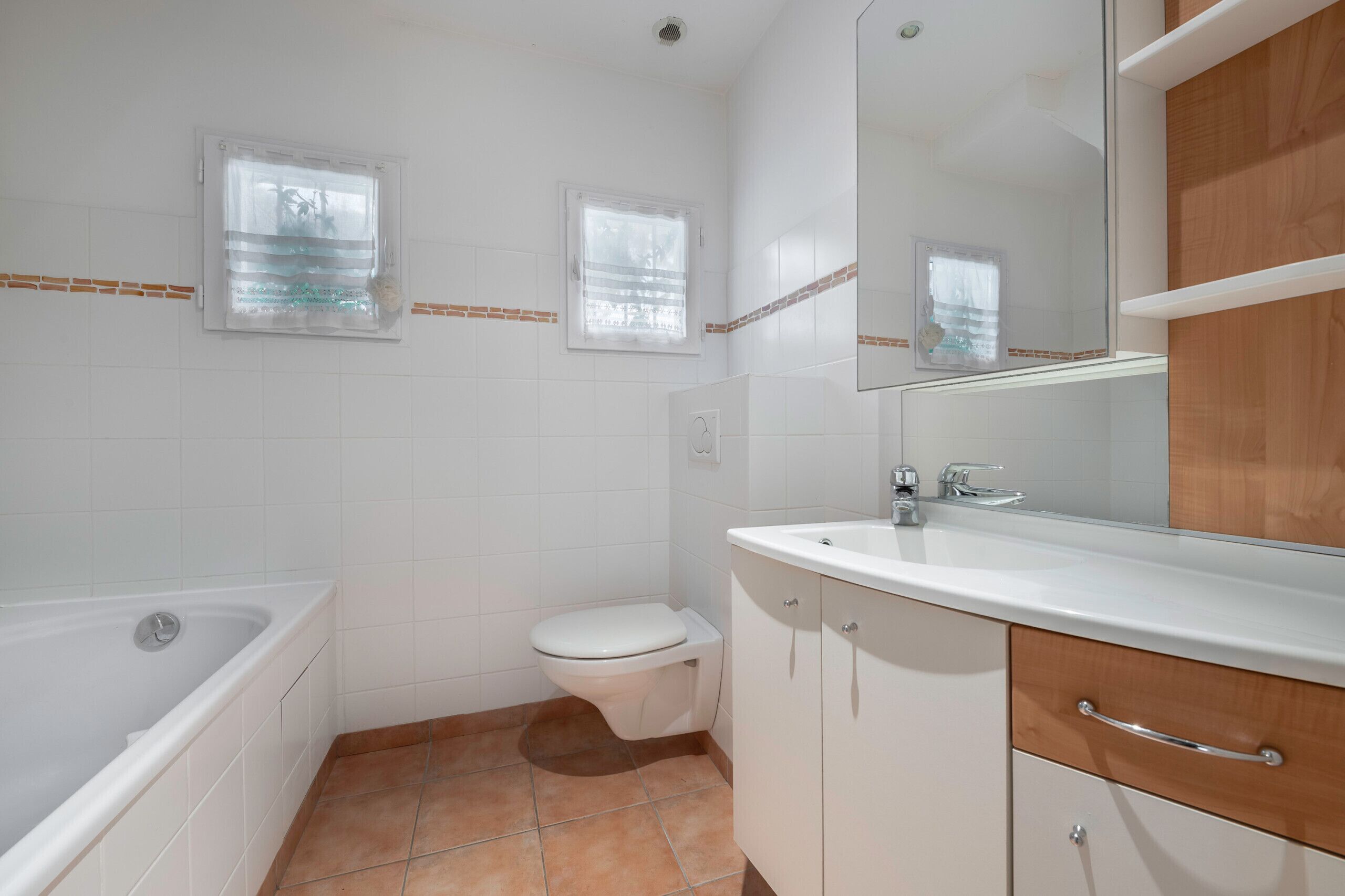 Un baño con bañera, inodoro y tocador con espejo.