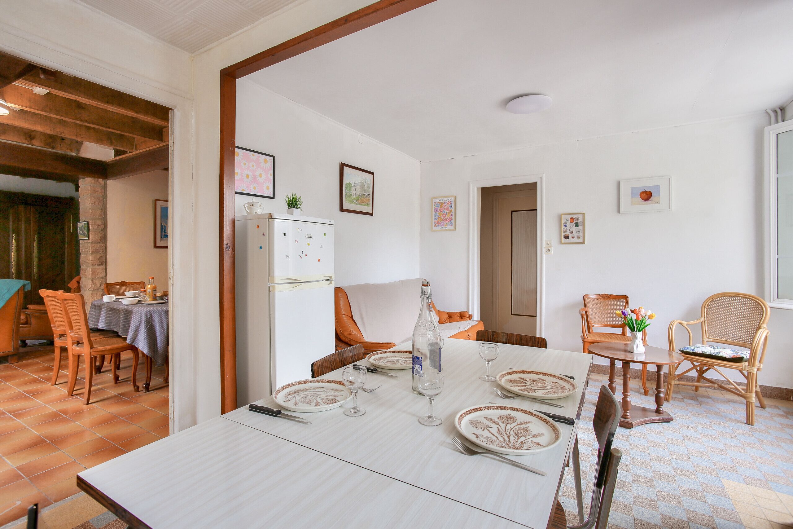 Un coin repas avec une table dressée pour quatre personnes, un réfrigérateur et une table à manger avec des chaises.