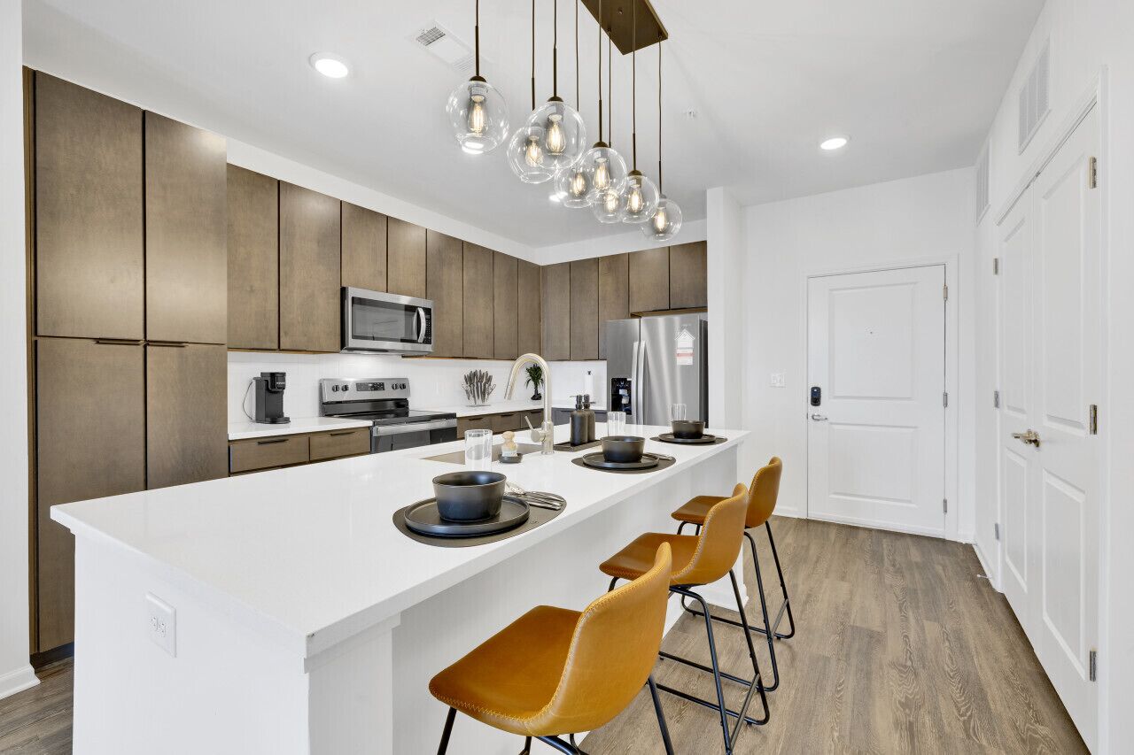 A modern kitchen with a central island, stainless steel appliances, and pendant lighting.
