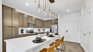 A modern kitchen with a central island, stainless steel appliances, and pendant lighting. - Spacious Oasis w/ Pool, Gym, & Stunning City Views (Birmingham)