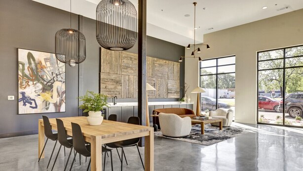 A modern interior with a wooden dining table, black chairs, a potted plant, a sofa, and a large window offering a view of parked cars. - Spacious Oasis w/ Pool, Gym, & Stunning City Views (Birmingham)