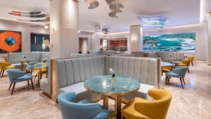 A modern hotel lobby with a central seating area, a large TV screen, and a unique ceiling design. - Yishang Hotel (Shanghai Hongqiao International Exhibition Center Jiangqiao Wanda Branch) (Shanghai)