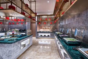 Un buffet proposant une variété de plats, avec plusieurs stations de service, un comptoir en marbre et un aménagement intérieur moderne.