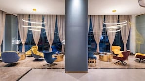 A modern lobby with a central column, round tables, and contemporary chairs. - Yishang Hotel (Shanghai Hongqiao International Exhibition Center Jiangqiao Wanda Branch) (Shanghai)