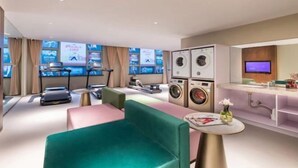 A modern hotel room with a sofa, a small table, a washing machine, a television, and a large window. - Yishang Hotel (Shanghai Hongqiao International Exhibition Center Jiangqiao Wanda Branch) (Shanghai)