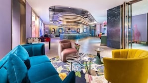 A lobby with a reception desk, a sofa, a chair, and a decorative table. - Yishang Hotel (Shanghai Hongqiao International Exhibition Center Jiangqiao Wanda Branch) (Shanghai)