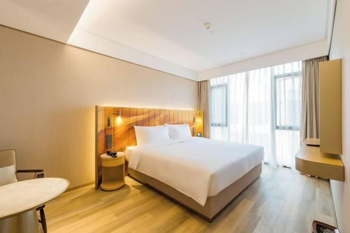 Una habitación de hotel con una cama grande, una mesita de noche, una silla y un televisor.