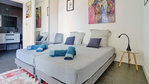 A modern bedroom with two beds, a desk, and a bathroom. - Sérénité au fil de L'eau: Appartement de Standing (L'Isle-sur-la-Sorgue)
