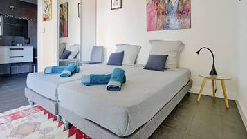Une chambre moderne avec deux lits, un bureau et une salle de bain.
