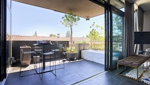 A modern patio with a dining set, a cushioned bench, and a potted plant. - Sérénité au fil de L'eau: Appartement de Standing (L'Isle-sur-la-Sorgue)