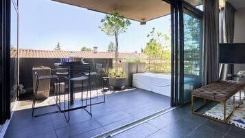 Une terrasse moderne avec un ensemble de mobilier de jardin, un banc rembourré et une plante en pot.
