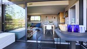 A modern interior with a dining area, a sofa, and a view of the outdoors. - Sérénité au fil de L'eau: Appartement de Standing (L'Isle-sur-la-Sorgue)