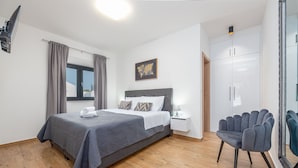 Une chambre à coucher moderne avec un grand lit, une table de chevet, une chaise et une armoire.