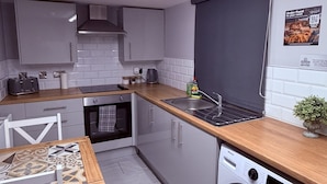 Una cocina compacta con horno integrado, lavadora y comedor con mesa estampada.