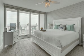 A bedroom with a large bed, a desk, a chair, and a view of the ocean through a sliding door. - Pool & Beach Access: Oceanfront Galveston Condo (Galveston)