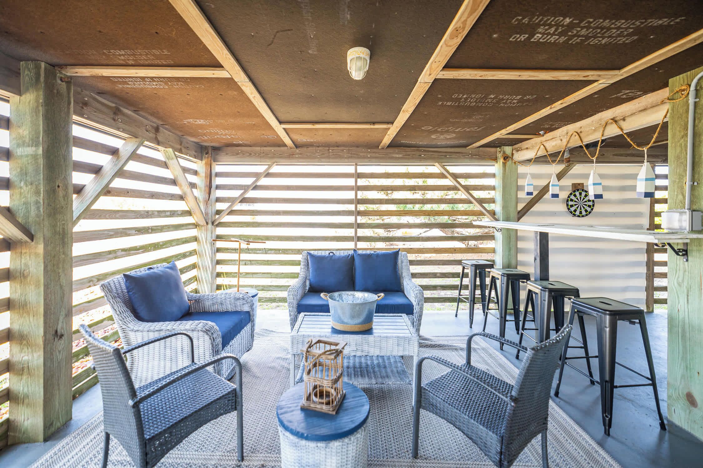 An outdoor patio with wicker furniture, a table, and a dartboard.