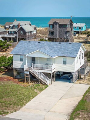 A beachfront house with a covered porch, a small deck, and a view of the ocean.