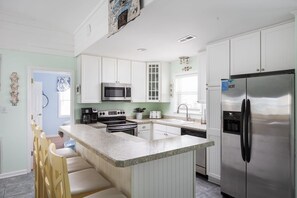 A modern kitchen with white cabinets, stainless steel appliances, and a granite countertop.