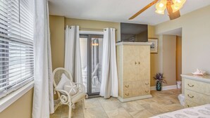 Une chambre à coucher comprenant un lit, une armoire, une chaise, une fenêtre avec des stores et un ventilateur de plafond.
