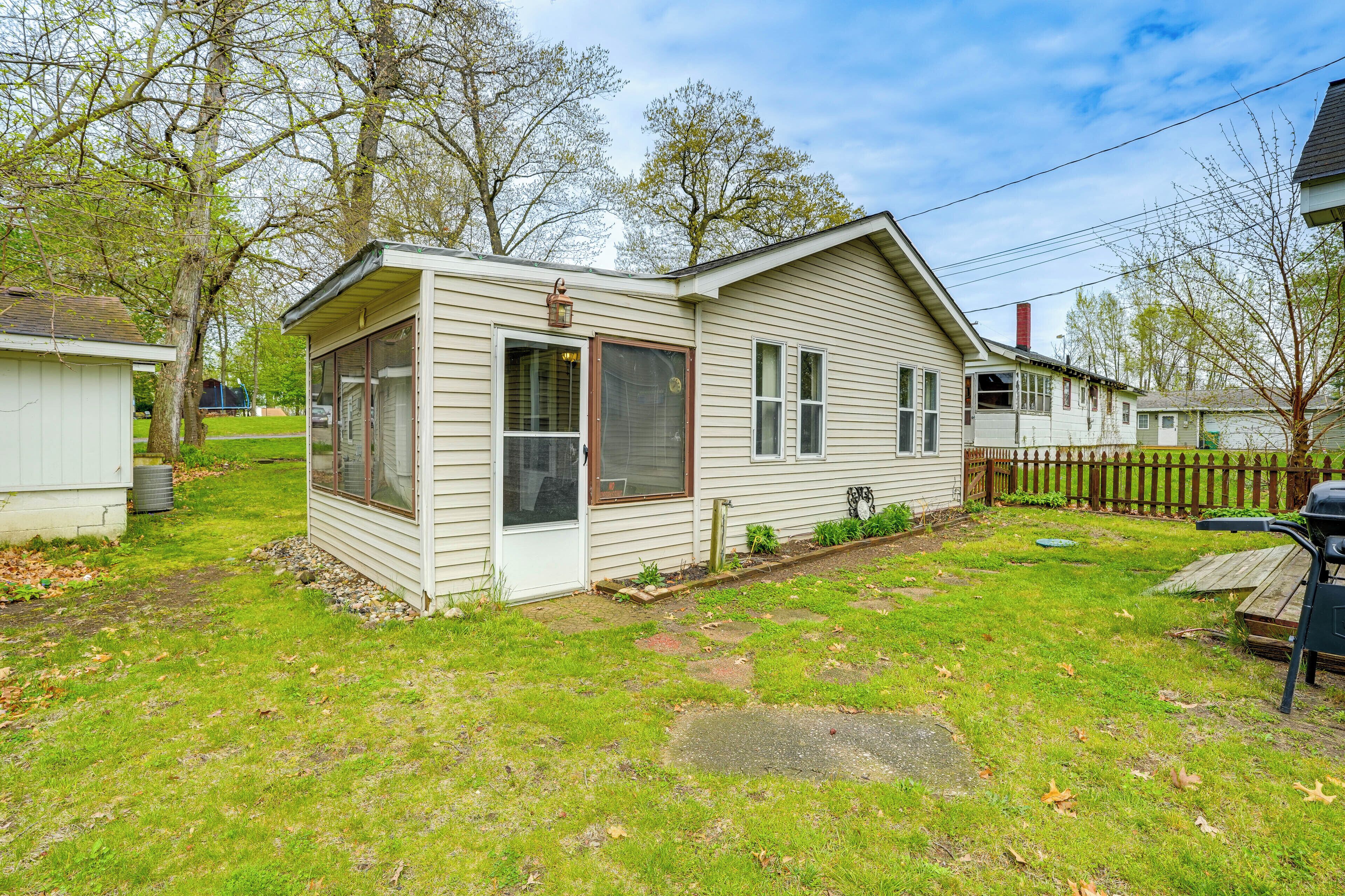 A single-story house with a front porch, a small attached garage, and a fenced backyard.