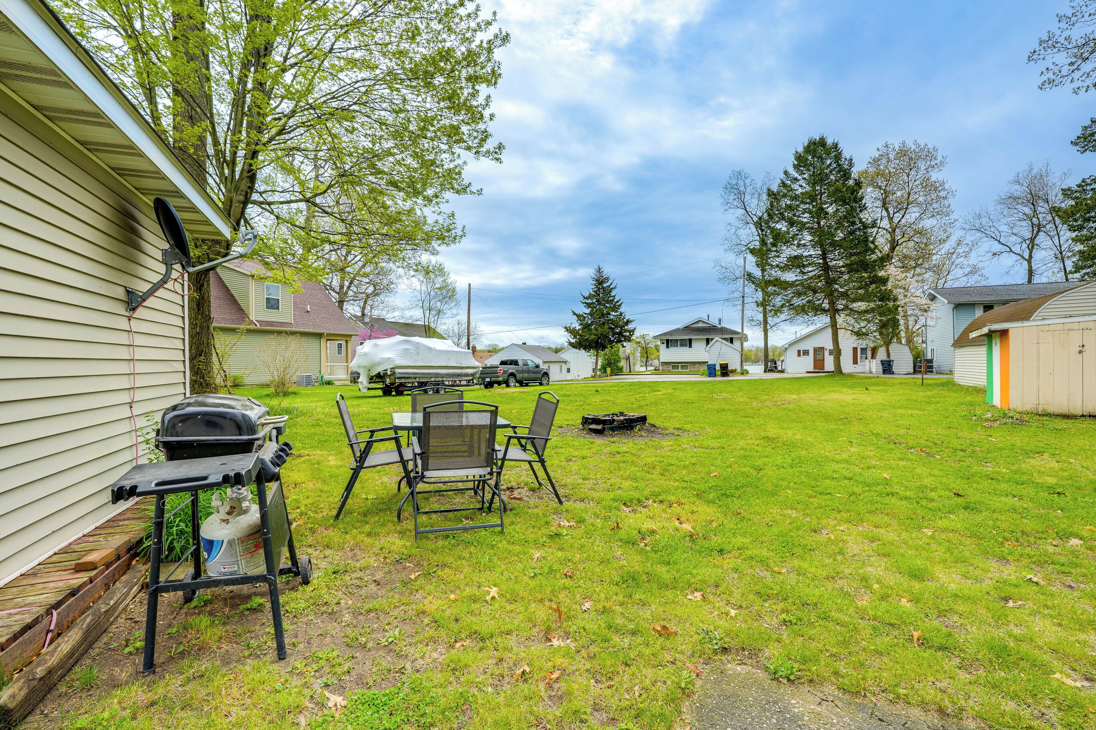 A backyard with a grill, chairs, and a table.