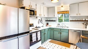 A modern kitchen with stainless steel appliances, teal cabinets, and a window providing natural light. - Vibrant Tacoma Retreat, Near Point Defiance Park! (Tacoma)