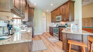 A kitchen with wooden cabinets, a microwave, a stove, and a coffee maker. - Wilmington Home w/ Sunroom & Private Deck! (Wilmington)