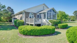 A two-story house with a covered porch and a deck, surrounded by well-maintained hedges and a lawn. - Wilmington Home w/ Sunroom & Private Deck! (Wilmington)