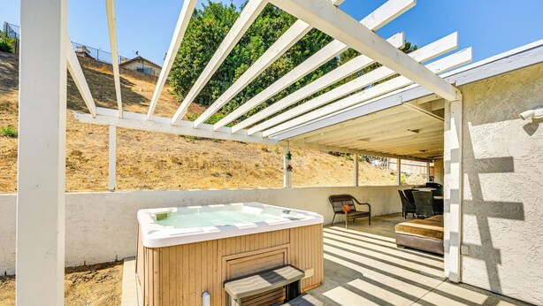 A hot tub under a pergola with a patio area, outdoor seating, and a view of a hillside. - Fireplace, Hot Tub, Patio & Bbq: San Diego Home (Spring Valley)