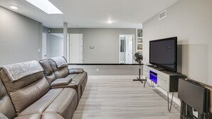 A modern living room with a leather sofa, a flat-screen TV, and a minimalist design. - Fireplace, Hot Tub, Patio & Bbq: San Diego Home (Spring Valley)