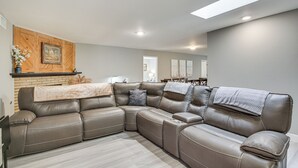 A sectional sofa with a built-in console table, a wooden accent wall, and a skylight. - Fireplace, Hot Tub, Patio & Bbq: San Diego Home (Spring Valley)