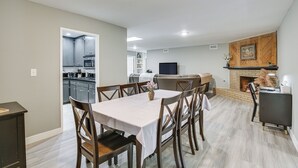 A modern kitchen with dark cabinets and a microwave, a dining area with a table and chairs, and a fireplace with a mantel. - Fireplace, Hot Tub, Patio & Bbq: San Diego Home (Spring Valley)