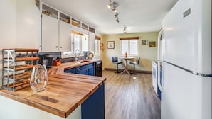 Een keuken met houten aanrecht, een koelkast en een eethoek met twee stoelen en een tafel.