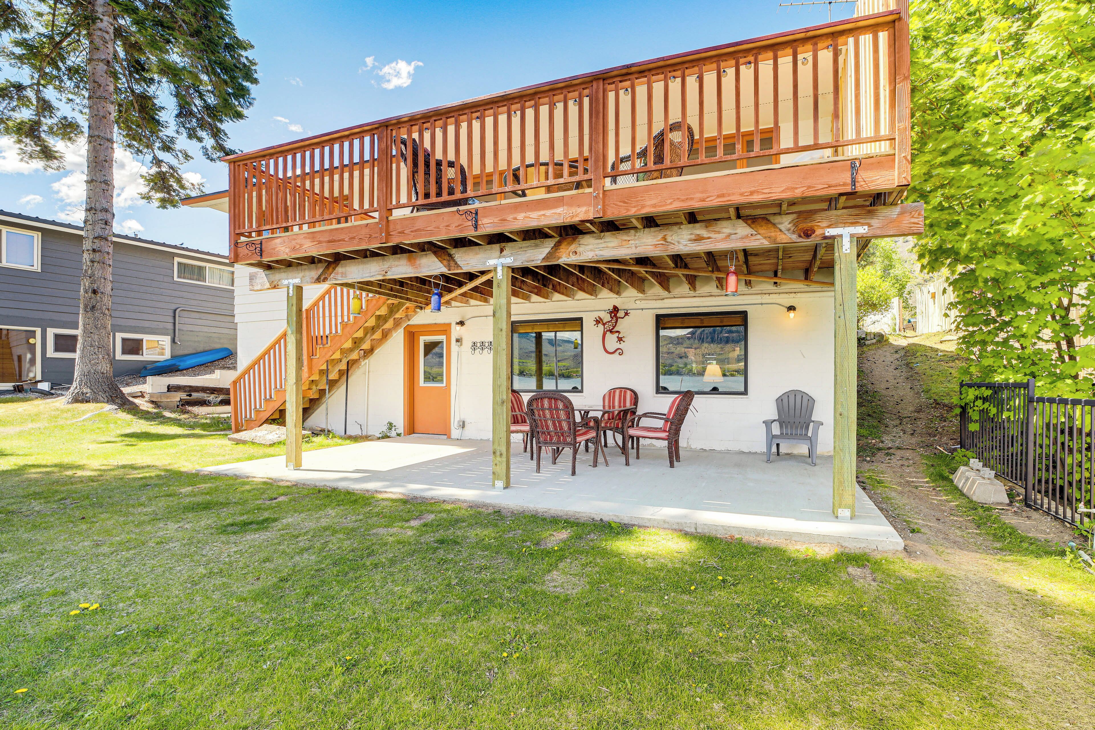 A two-story house with a balcony, a covered patio with outdoor furniture, and a staircase leading to the upper floor.