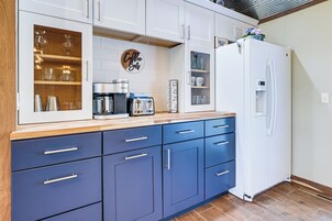 Una cocina moderna con armarios blancos, encimera azul y refrigerador blanco.