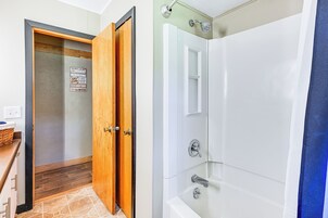 Un baño con ducha, puerta de madera y suelo de baldosas.