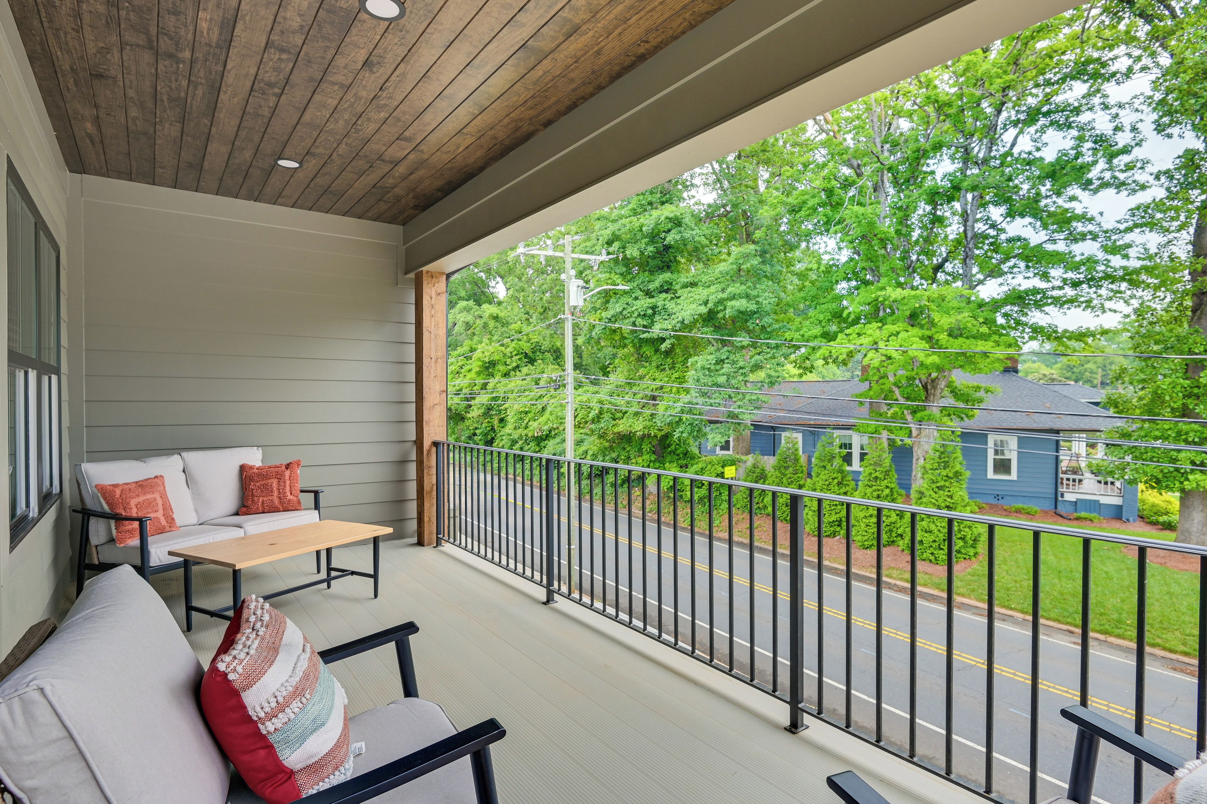 A covered porch with a wooden ceiling, a bench, and a table.