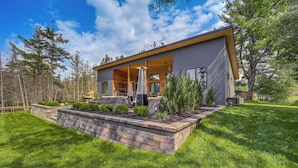 Une maison moderne dotée d’un grand patio ouvert, d’un mur de soutènement en pierre et d’une pelouse bien entretenue.