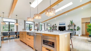 Une cuisine moderne avec des meubles en bois, des appareils électroménagers en acier inoxydable et des luminaires suspendus.