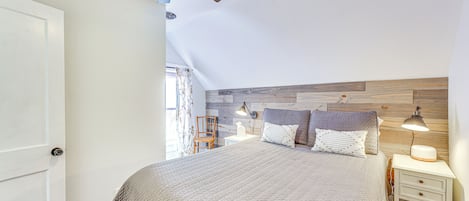 A bedroom with a bed, bedside table, lamp, and ceiling fan.