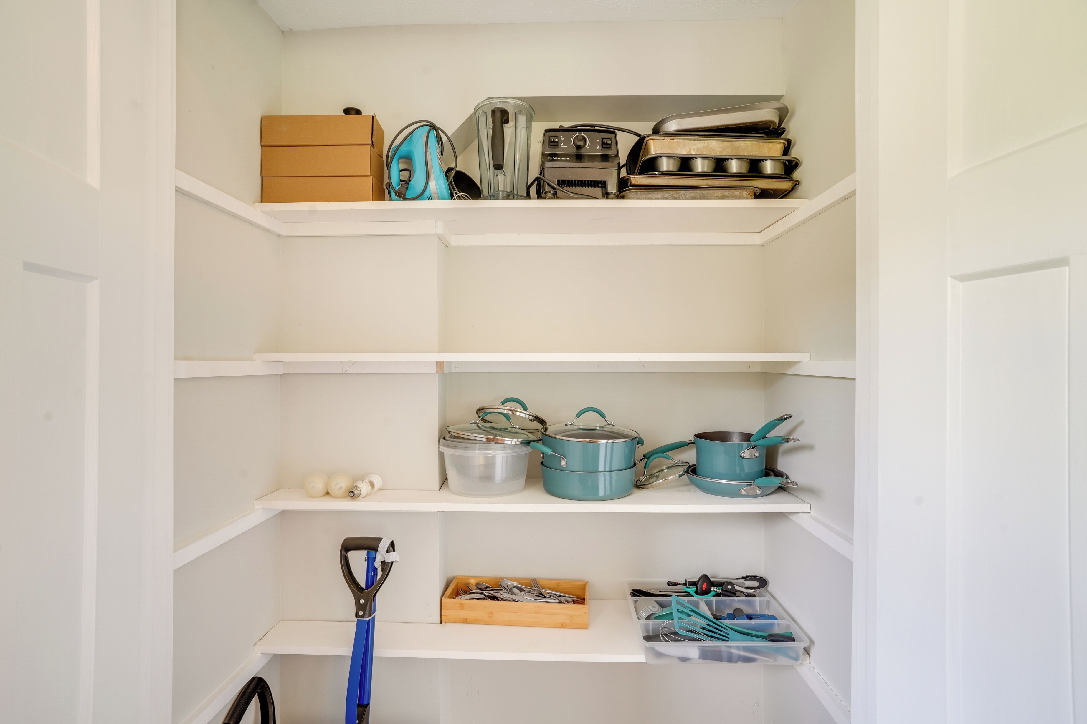 A kitchen with white cabinets, a blue kettle, and various kitchen utensils.