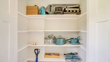 A kitchen with white cabinets, a blue kettle, and various kitchen utensils.