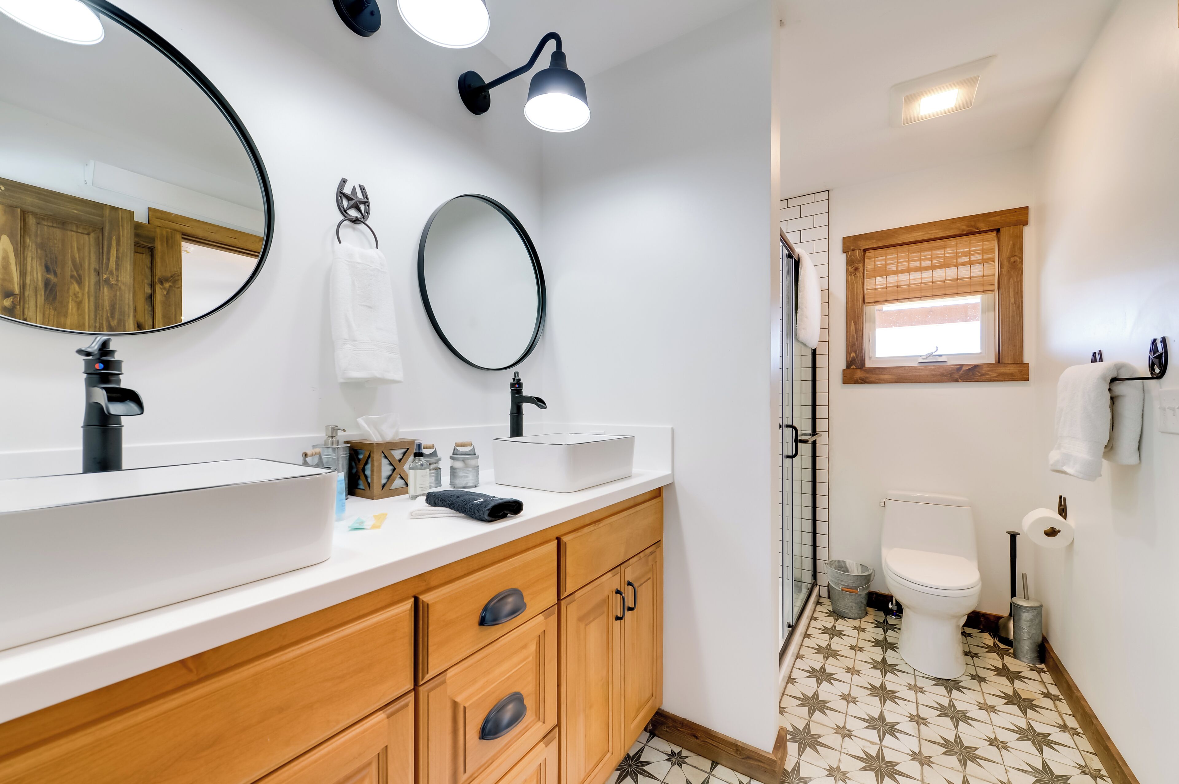A bathroom with two sinks, a large mirror, and a window.
