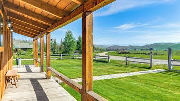 A wooden deck with a bench, overlooking a grassy area with a fence and a clear sky.