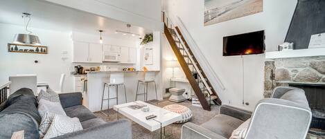 A modern living room with a grey sofa, a white coffee table, and a fireplace.