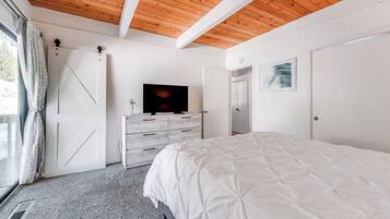Un dormitorio con una cama grande, un televisor sobre una cómoda y un techo de madera.
