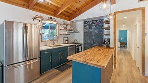 A modern kitchen with wooden beams, a stainless steel refrigerator, and a blue accent wall.