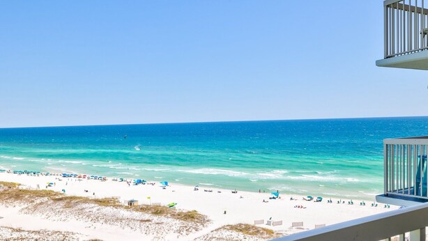 A beach view from a balcony with a railing, sandy beach, and ocean. - Pelican Beach 1115 2 Bedroom Condo (Destin)
