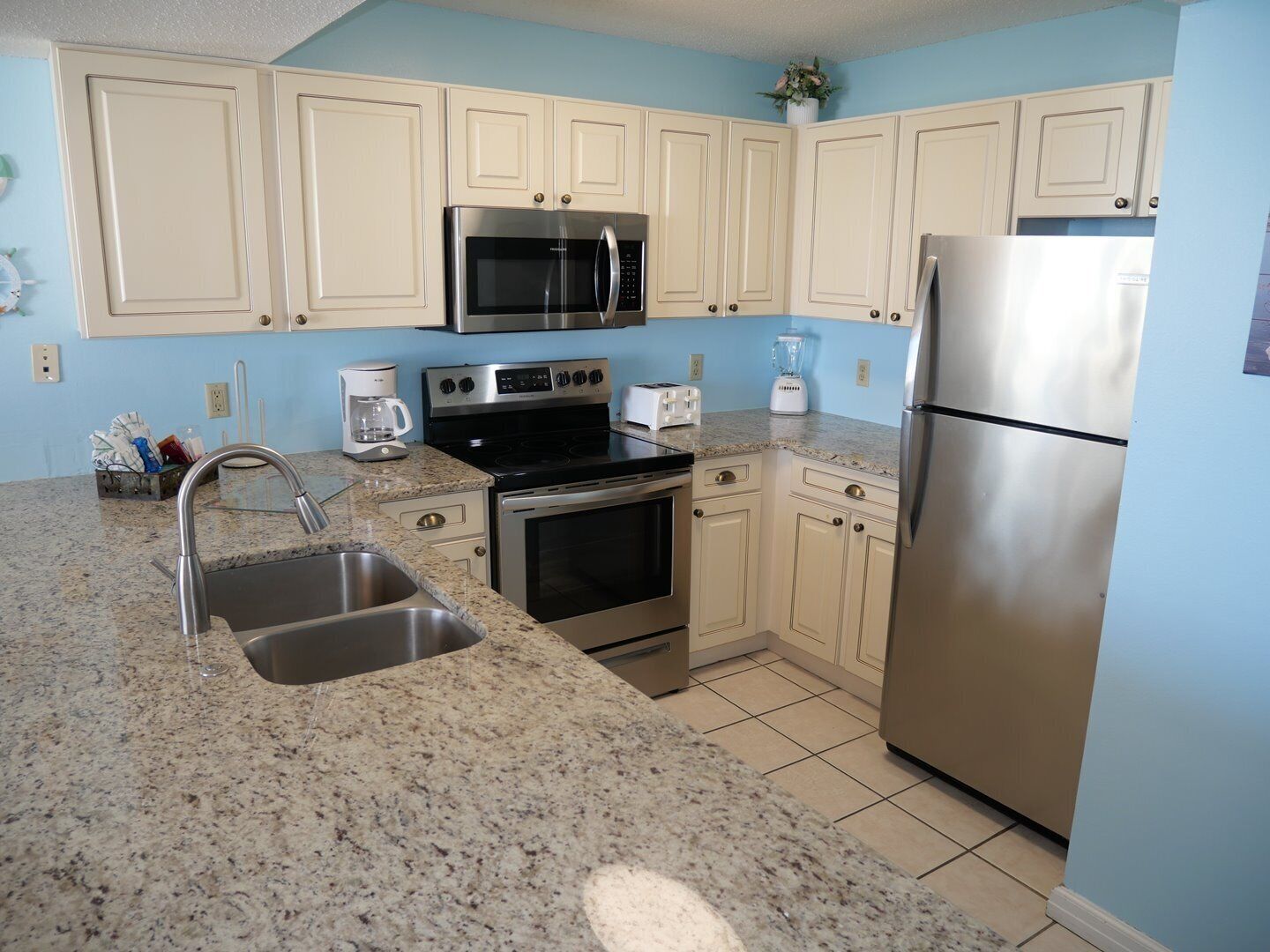 A kitchen with granite countertops, stainless steel appliances, and light blue cabinetry.
